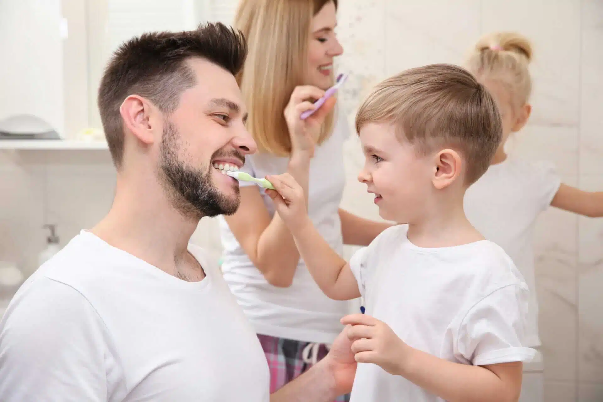 Family brushing teeth together in bathroom, promoting dental health. Southern Style Dental offers family dentistry services.