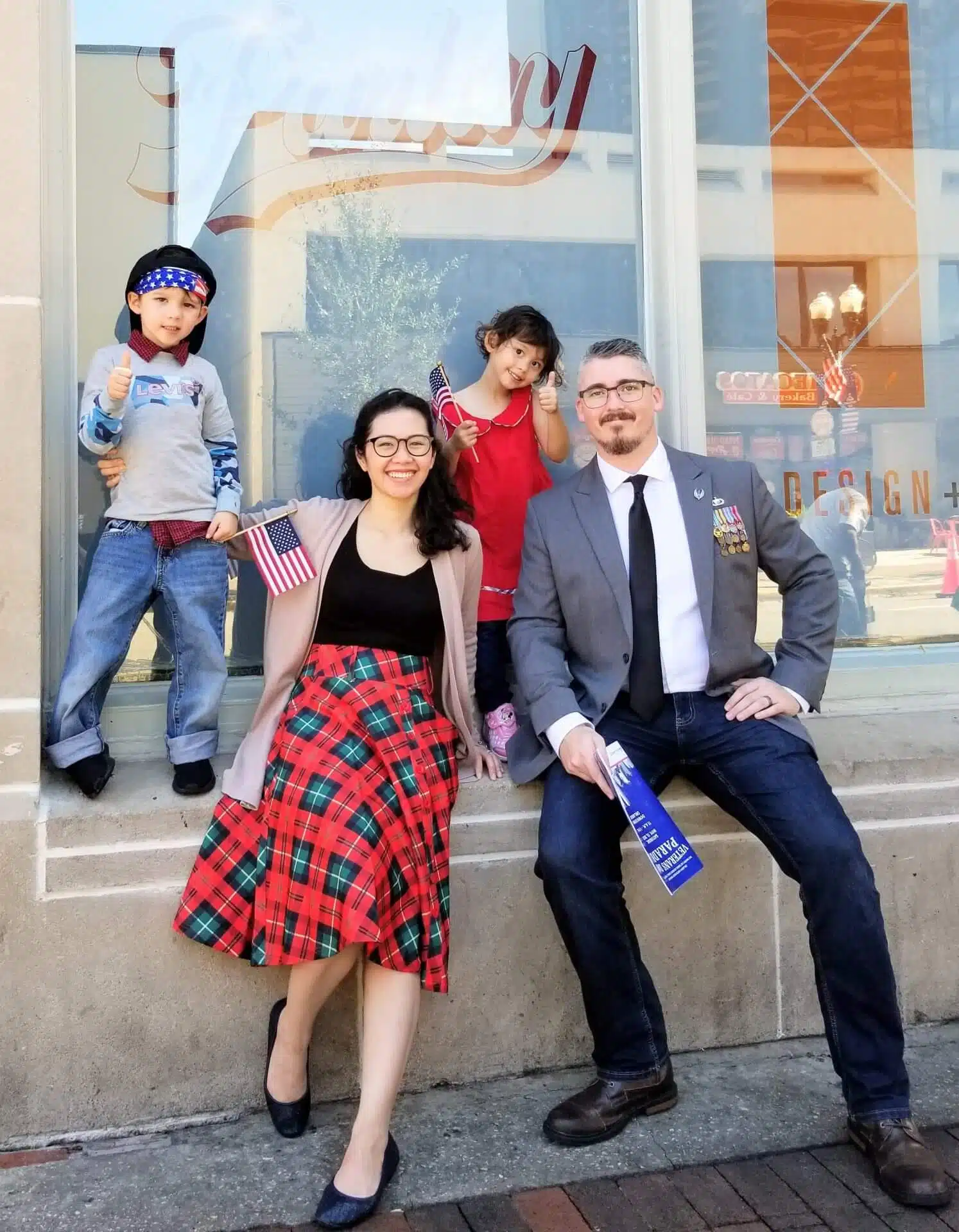Happy family outside Southern Style Dental office, showcasing smiles and holding American flags.