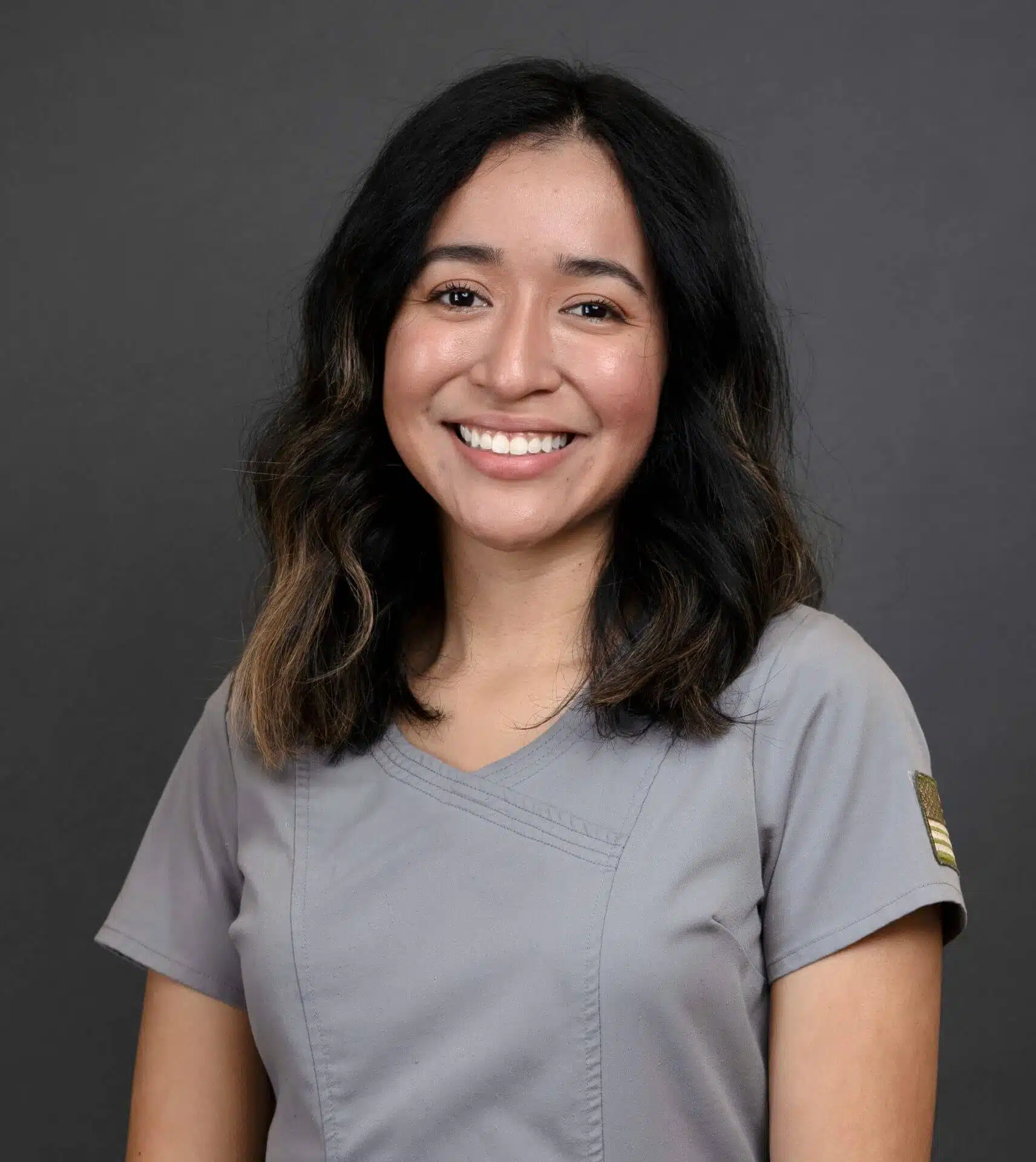 Female dental staff member smiling in gray uniform at Southern Style Dental.