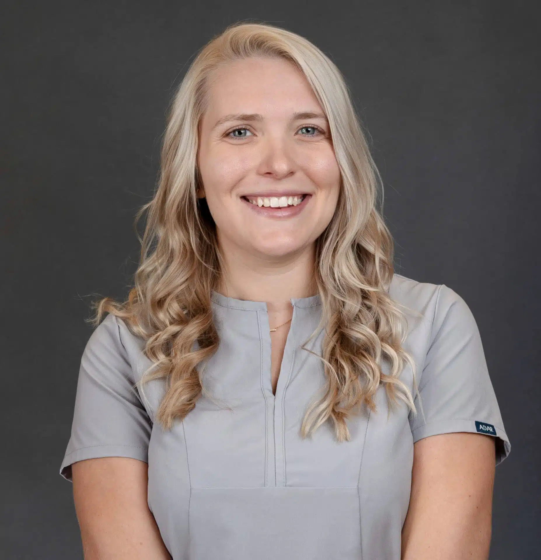 Smiling dental professional at Southern Style Dental in a gray uniform, providing quality care and friendly service.