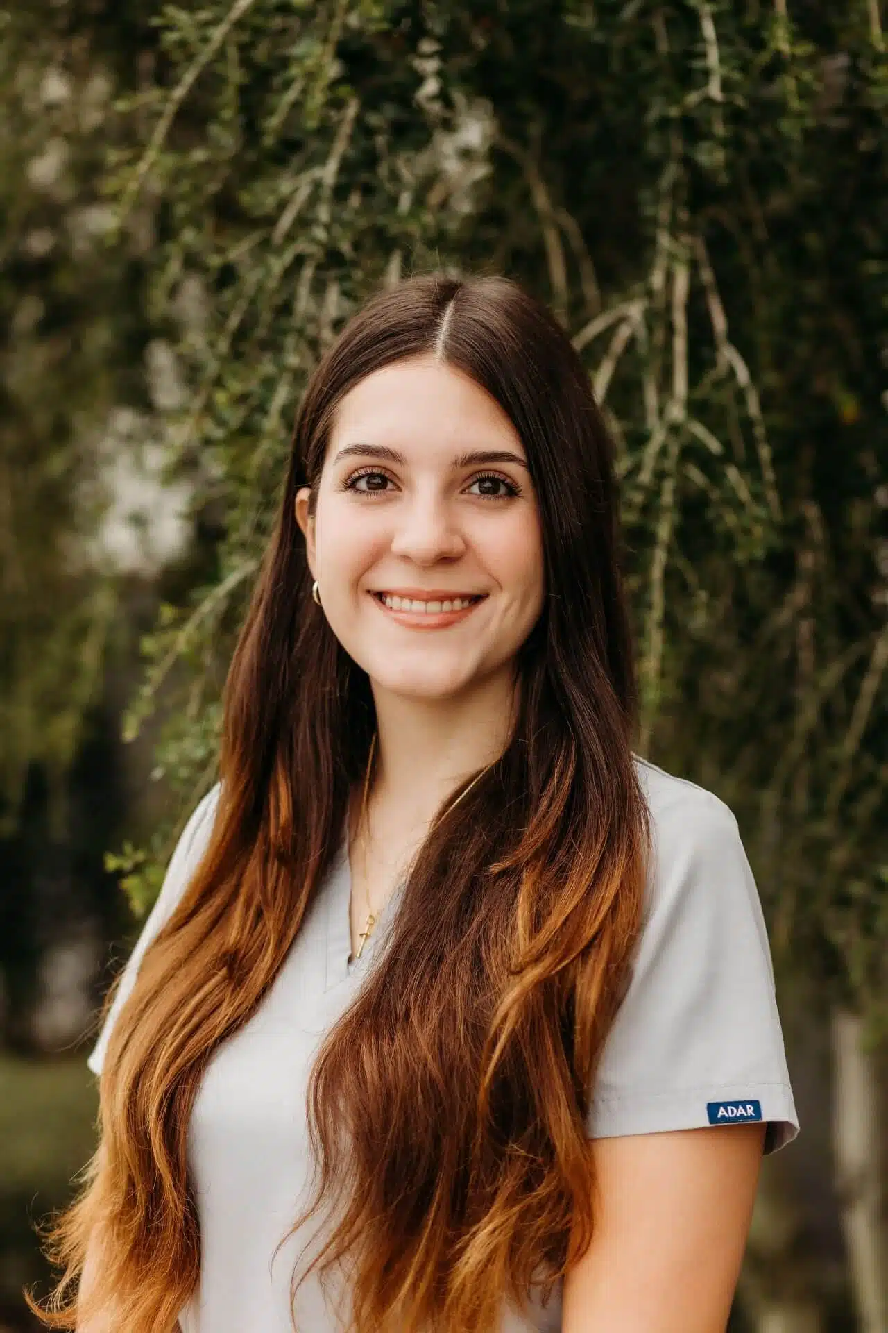 Smiling female dental professional at Southern Style Dental, providing quality care in a serene outdoor setting.
